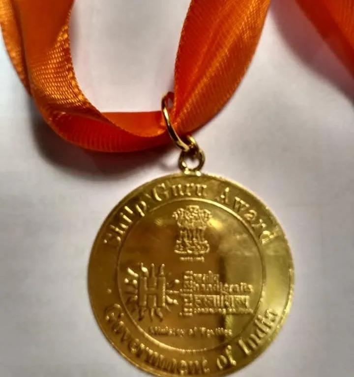 The gold Shilp Guru Award medal of the Government of India, on an orange ribbon