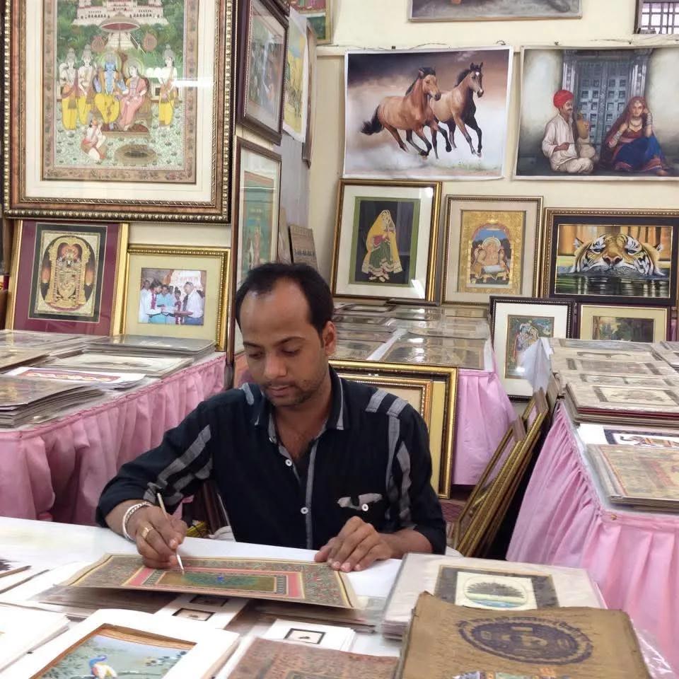 A painter at work at a table of miniatures, among framed paintings of horses and figures