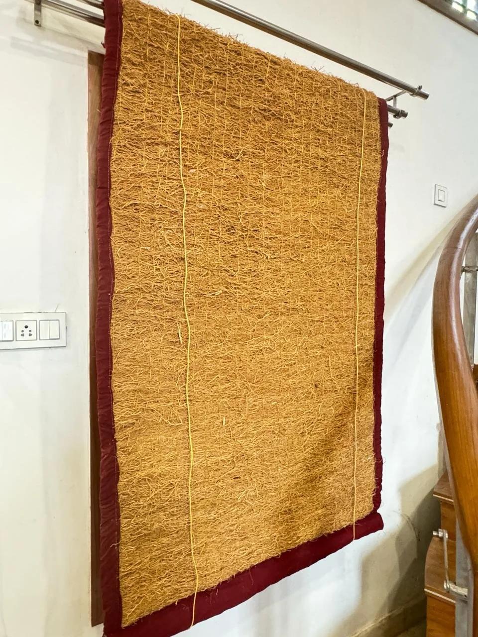 A khus (vetiver) curtain with a maroon border hanging in a doorway