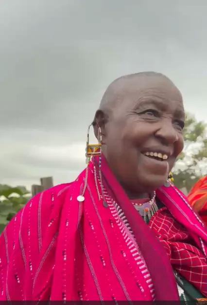 A smiling Maasai elder in a pink shúkà with beaded earrings and necklace